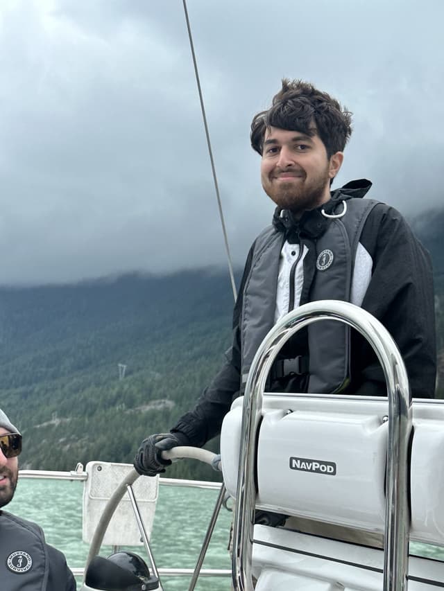 A picture of Payam Yektamaram steering a sail-boat in Squamish, British Columbia.